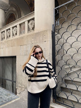 A lady wears a striped sweater.